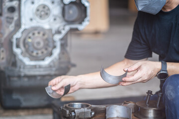 Mechanic man holding crankshaft of diesel commonrail engine in heavy machinery workshop
