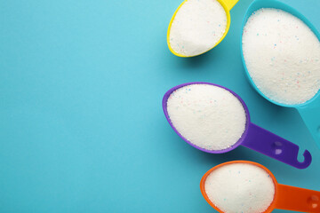 Measuring scoop with laundry powder on blue background.