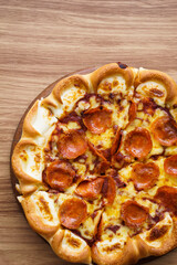 Vertical and part of cheese pizza on wood tray and backdrop, view from above, top view