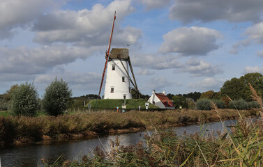 View of the picturesque Schellemolen (Windmill), in Damme near Bruges in West Flanders, Belgium. Lovely early autumn landscape. Reflections in the still water of the Damse vaart (Canal).