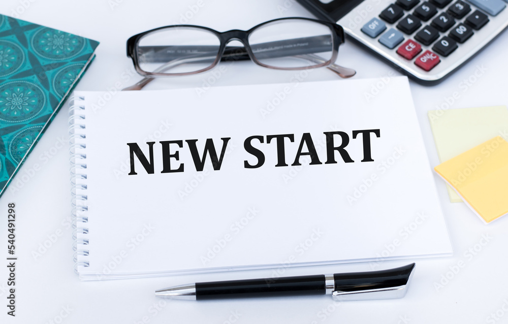 Poster new start text on a notepad on the table next to glasses, calculator and documents