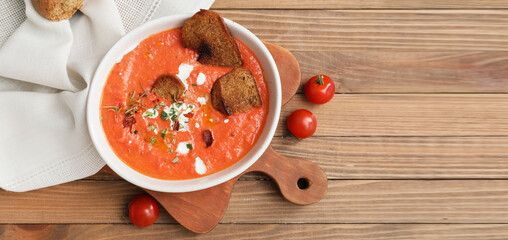 Bowl of tomato cream soup on wooden background with space for text