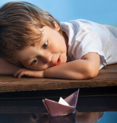 boy play in paper ship in water puddel
