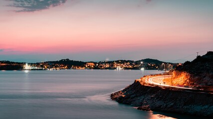 Sunset in Vouliagmeni Athens Greece. Seaside road with trail lights from the moving cars.