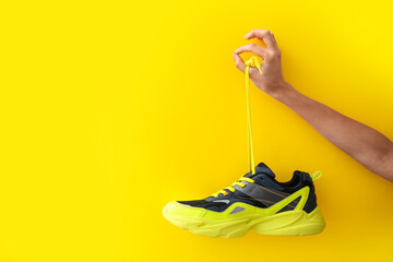Woman holding modern shoe and showing OK gesture on yellow background - obrazy, fototapety, plakaty