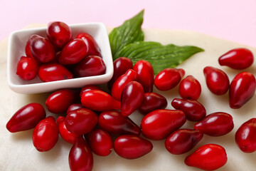 Bowl with ripe red dogwood berries and leaves on light background, closeup