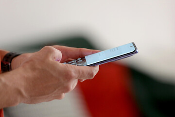 A man writes a text message on his phone. Person texting text message using in hands mobile phone, closeup.