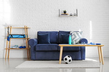 Stylish interior of light room with sofa and sport equipment