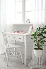 Makeup artist's workplace with different decorative cosmetics near light wall in room interior