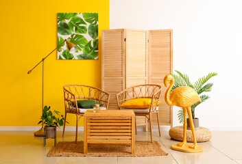 Stylish interior of room with wicker chairs and golden flamingo near color wall