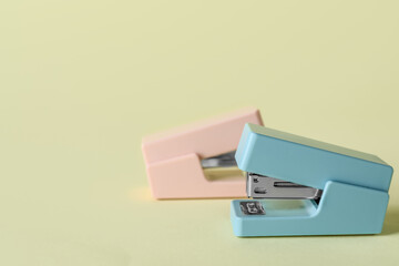 Office staplers on color background