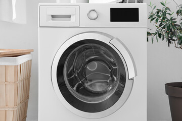Modern washing machine near light wall in laundry room, closeup