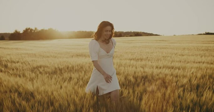 Beautiful Ukrainian young woman walking alone in yellow wheat meadow. Brunette girl in peace with summer nature. Relax freedom concept. Peaceful happy Ukraine. Floral landscape outdoors 4k slow motion