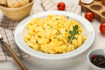 Plate of tasty scrambled eggs on light table, closeup