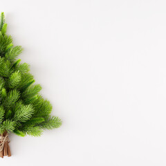 Christmas tree concept. Creative layout made of fir branches and  cinnamon sticks on white background with copy space. Minimal flat lay. New Year holiday idea.