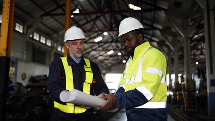 Engineers in discussion in machine maintenance in factory. Group of Industrial Engineers with Blueprint against trains and machinaries industry background. Studying Blueprint with Superior