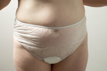 Female postpartum belly in disposable underpants, hygiene