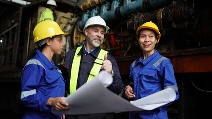 Fototapeta premium Engineers in discussion in machine maintenance in factory. Group of Industrial Engineers with Blueprint against trains and machinaries industry background.
