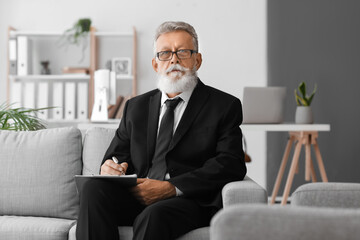 Male psychologist with clipboard video chatting in office