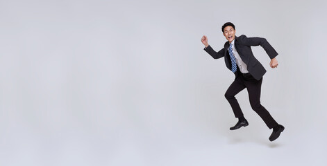 handsome happy energetic young Asian businessman jumping in mid-air isolated on white copy space background.