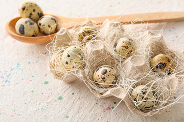 Cardboard holder with raw quail eggs on light background, closeup