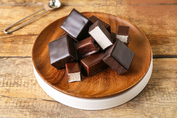 Plate with tasty bird's milk candies on wooden table