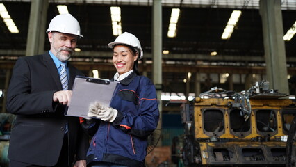 Factory manager or businessman and female engineer in factory. elegant man inspecting factory in industry plant background.