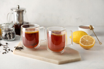 Board with glass cups of black tea and lemon on white background, closeup