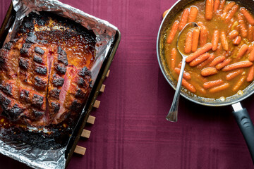 Top down view of roasted smokey picnic ham served with sauteed carrots.