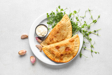 Plate with tasty chebureks, sauce and green sprouts on light background