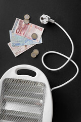 Money with electric fan heater on black background. Heating season concept