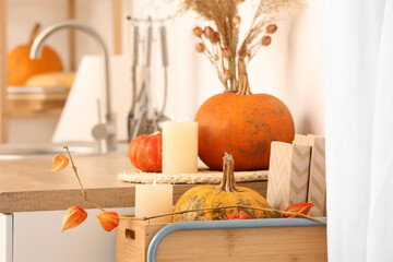 Counter with pumpkins, candles and vase in light kitchen