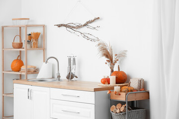 Interior of light kitchen with counters, shelving unit and pumpkins