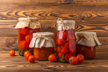 Pickled tomatoes, sun-dried tomatoes and canned lecho in a jar on a brown wooden table. Food supplies. Healthy food. Harvesting. copy space. Place for text.