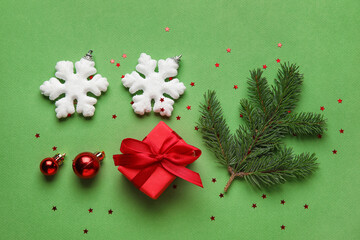 Composition with fir branch, Christmas decorations and gift on green background