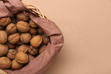 Basket with fresh walnuts on color background