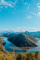 Aerial panoramic view of landscape of green mountains with river and blue sky with white clouds, Montenegro. Travel trip background for a post, screensaver, wallpaper, poster, banner, cover, website