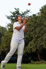 Girl wearing cricket uniform catching the ball on the field