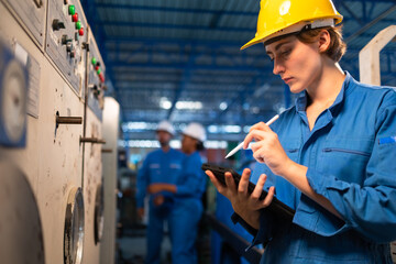 Young female worker  in protective uniform operating machine at factory Industrial.People working in industry.Manufacturing plant on background