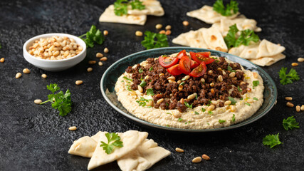 Hummus with spiced ground beef, olive oil, tomatoes and toasted pine nuts