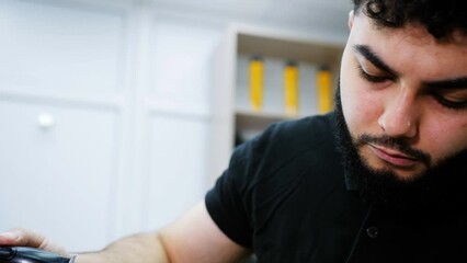 Barber shave the back of the head of a male client with a trimmer.