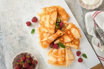 Pancakes. Stack of crepes or thin pancakes with berries, with raspberries and honey for breakfast. Homemade breakfast. Copy space. Selective focus.
