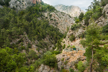 Tourists walk along river in Goynuk Canyon. Aerial view on mountain slopes in Beydaglari Coastal National Park. Turkey.