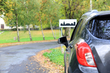 Bok samochodu osobowego, suwa od tyłu, znak drogowy, obszar zabudowany przy drodze.