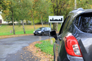 Bok samochodu osobowego, suwa od tyłu, znak drogowy, obszar zabudowany przy drodze.
