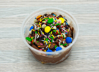 chocolate ice cream topping with vanilla chips, chocolate chips, sprinkles and bunties served in...