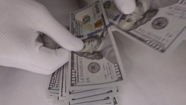 Man in gloves counts banknotes, new money falls on a pile