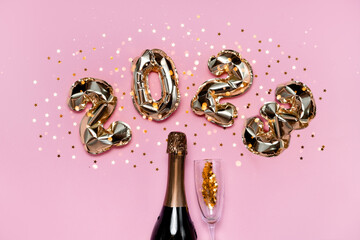 2023 golden foil balloons numbers, champagne, stars confetti, ribbons  and bokeh. Top horizontal view copy space new year and holiday concept.