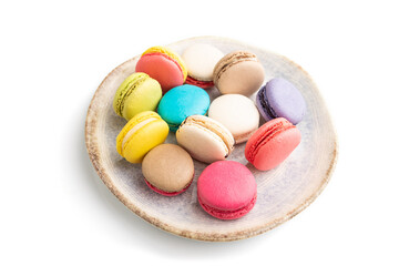 Different colors macaroons on ceramic plate isolated on white background. side view, close up.