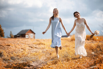 Naklejka na ściany i meble Two girls in dresses in autumn field